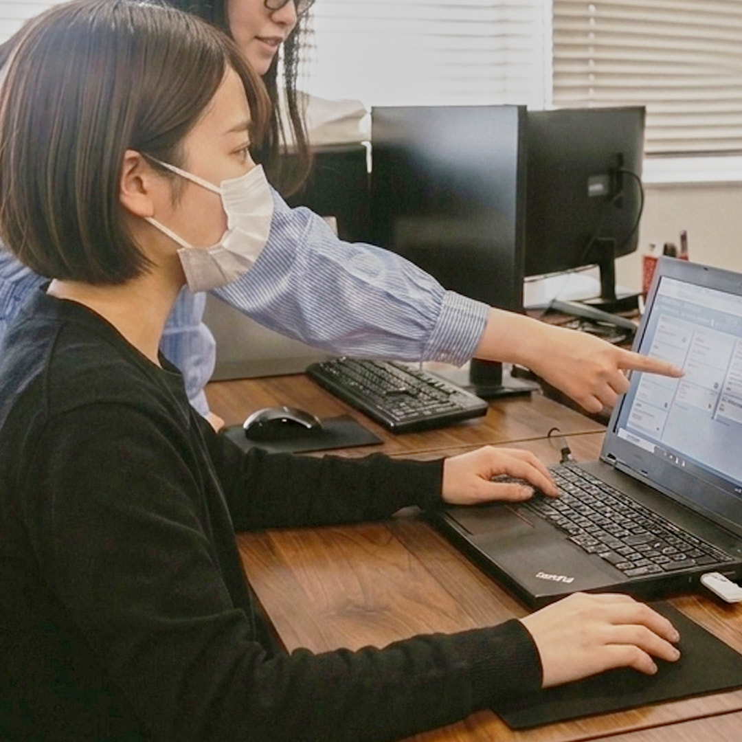 スタッフが画面を指しながら操作を教えている様子