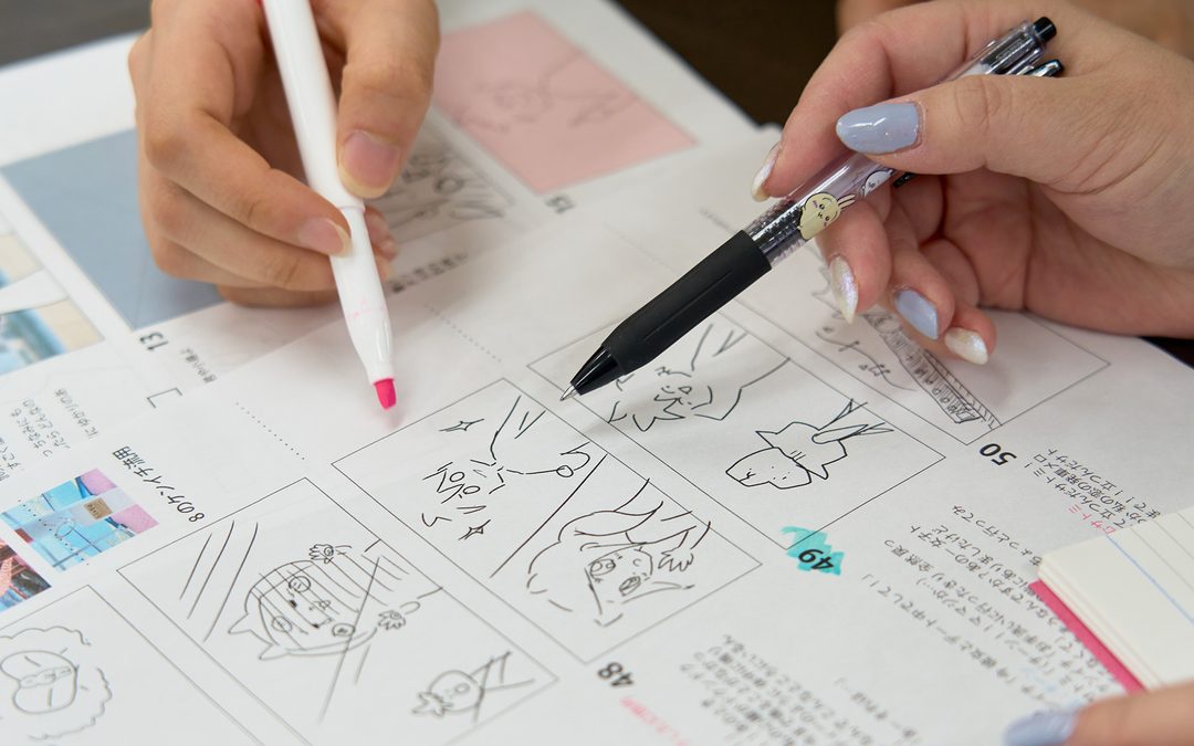 2人で絵コンテにペンを入れながら、動画の構成を組み立てているところ